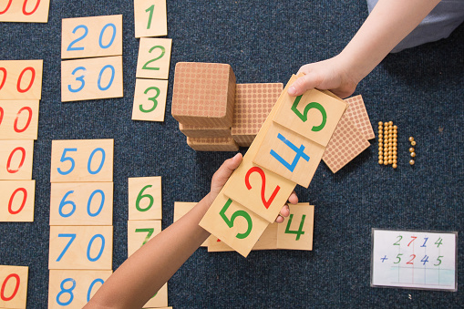 Montessori learning with numbers on wooden blocks hands reaching out for help