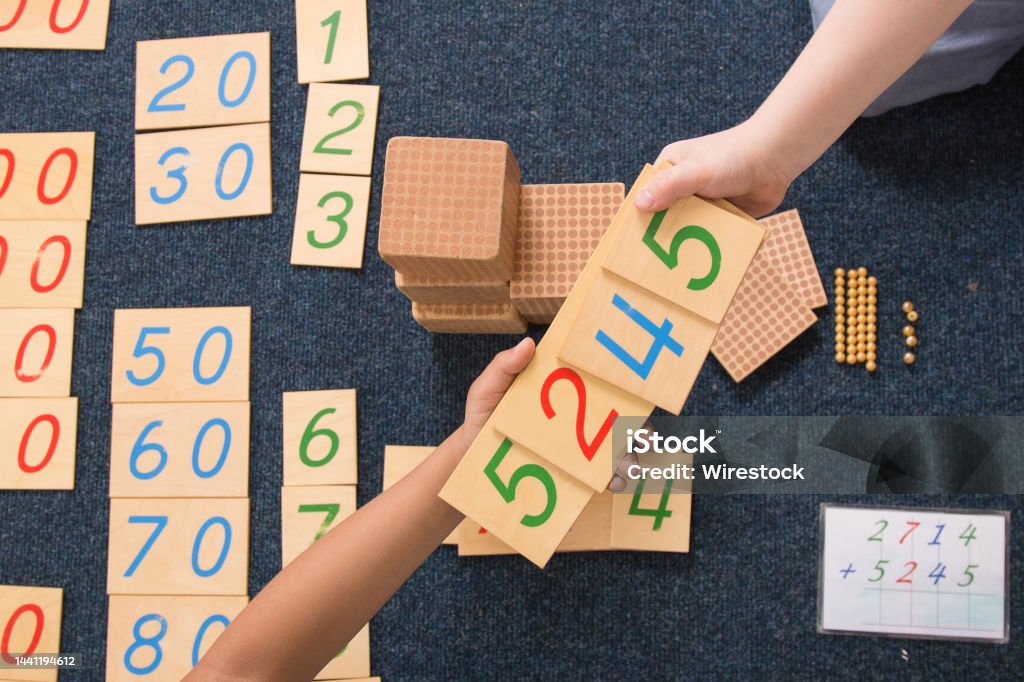 Montessori learning with numbers on wooden blocks Montessori learning with numbers on wooden blocks hands reaching out for help Montessori Education Stock Photo