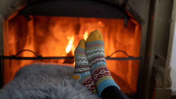 istock Two feet with warm socks on a pillow in front of a fireplace 1441194620