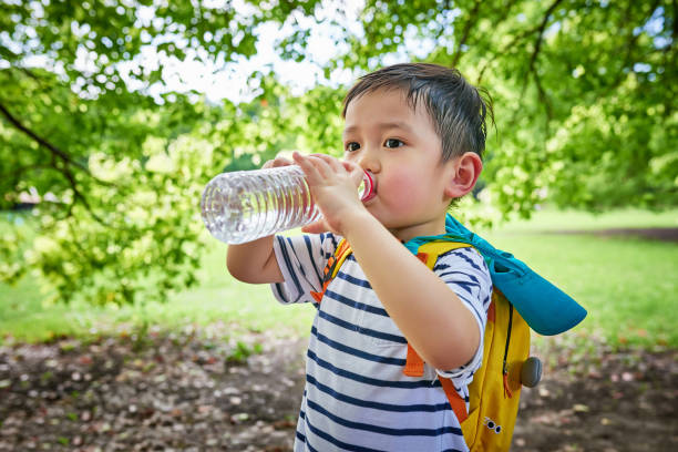 istock Close-up of Little Boy Drinking Water Under Tree 1441194669