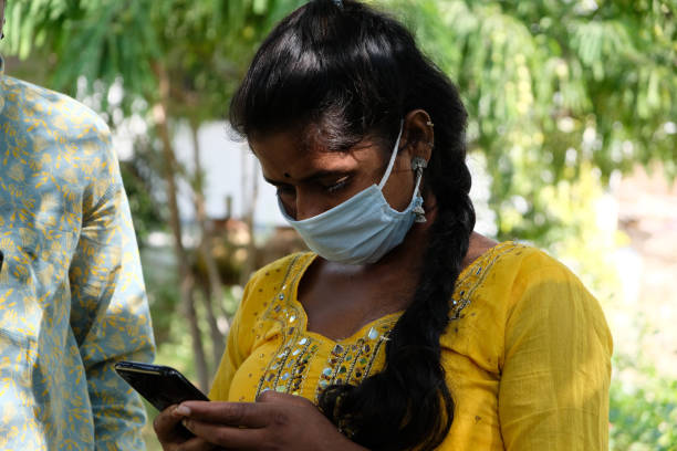 istock Portrait of a young Indian female with a long braid and a protective face mask using her phone 1441195021