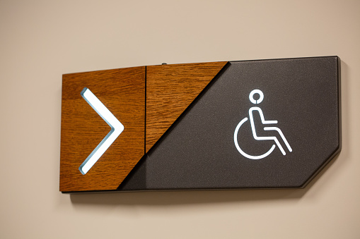The toilet sign for disabled people with direction arrow on the wall
