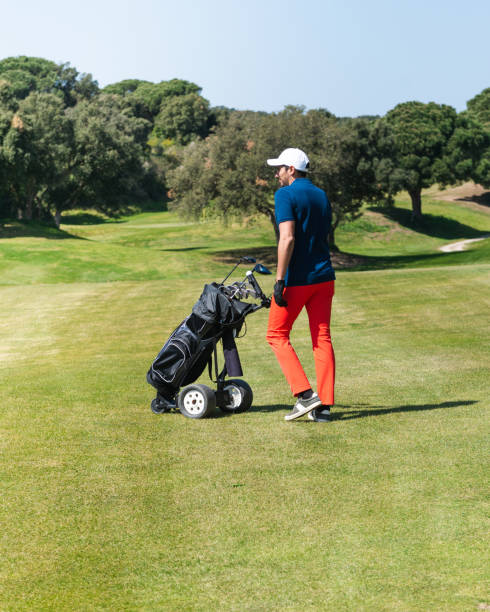 istock Young Caucasian male pulling the golf bag trolley on a golf course 1441196350