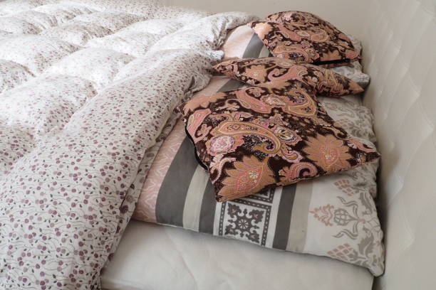 istock Pink decorative pillows on the bed linen. Double bridal bed with pillows and thick feather duvet. Bedroom design. Soft white headboard. Interior with furniture and bedding. 1441196906