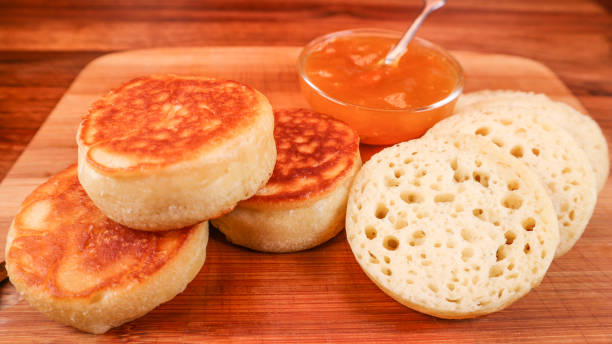 Closeup of sourdough crumpets with a dip on a wooden boar A closeup of sourdough crumpets with a dip on a wooden boar crumpets stock pictures, royalty-free photos & images