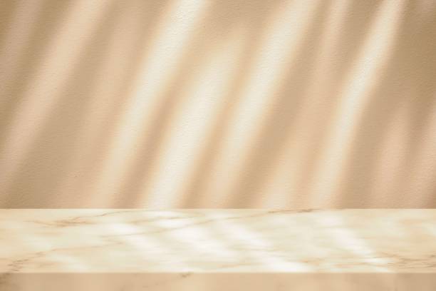 istock Marble Table with White Stucco Wall Texture Background with Shadow Line and Warm Light Beam, Suitable for Product Presentation Backdrop, Display, and Mock up. 1441198209
