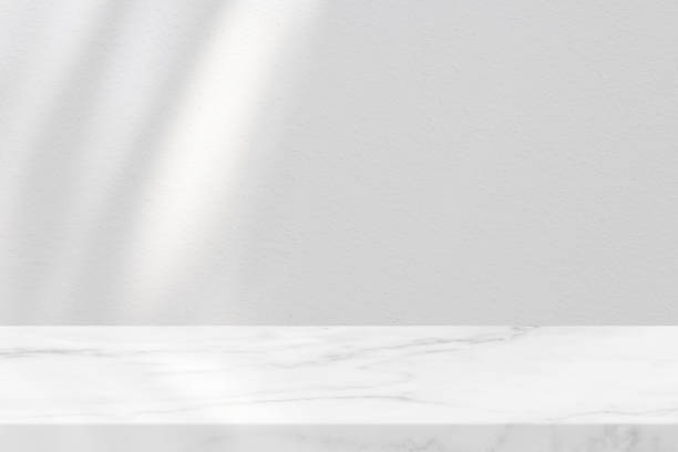 istock Marble Table with White Stucco Wall Texture Background with Shadow Line and Light Beam, Suitable for Product Presentation Backdrop, Display, and Mock up. 1441198808