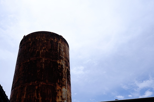 Old Rustic Water Tank with Cloudy Sky Background.