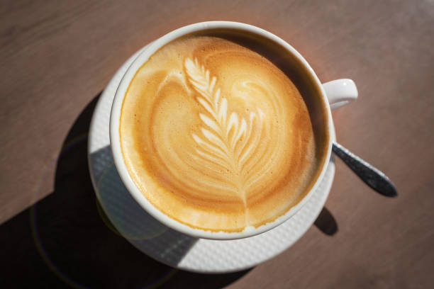istock Fresh cappuccino cup with drawn leaf standing on wooden table 1441203023