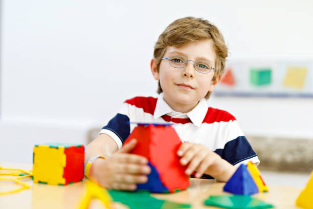 istock Happy kid boy with glasses having fun with building and creating geometric figures, learning mathematics and geometry 1441204135