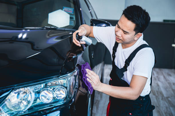 trabalhador usando um avental está pulverizando verniz de carro e usar um pano para polir os carros na garagem. - protective varnish - fotografias e filmes do acervo