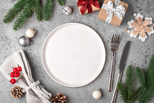 Christmas place setting and decorations on gray table.