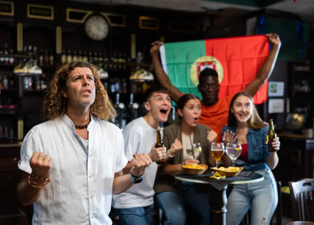 Photo of Emotional Portuguese man watching football match in sports bar