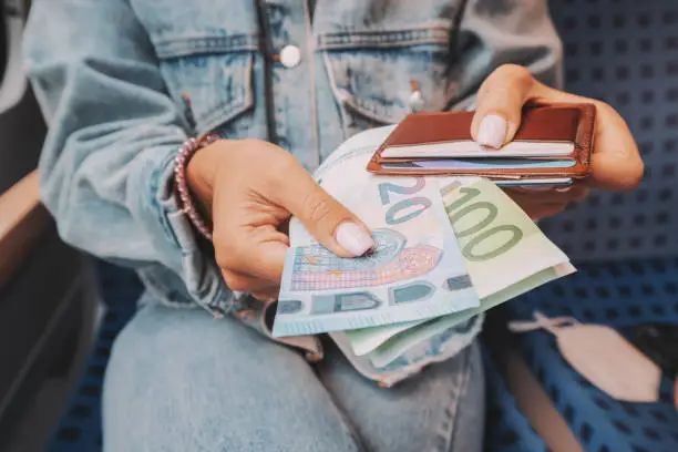 Photo of The girl takes euro banknotes out of her wallet. The concept of devaluation and inflation of the European currency