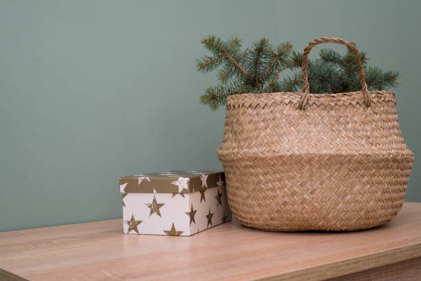 istock Straw basket with spruce branches and gift box on a wooden table. Christmas background. 1441215849