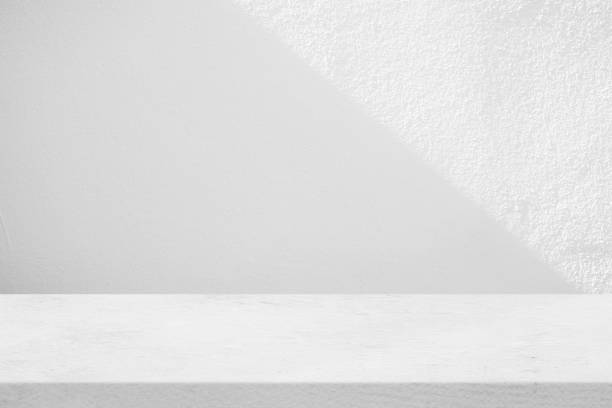 istock Concrete Table with White Stucco Wall Texture Background with Light Beam and Shadow, Suitable for Product Presentation Backdrop, Display, and Mock up. 1441219403