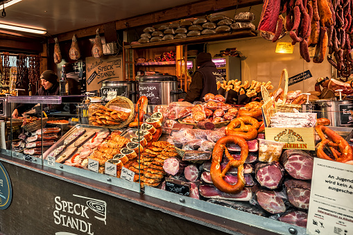 Vienna, Austria - December 04, 2019: Kiosk with different types of smoked and cured meat along with traditional bakery products during famous annual Christmas market taking place on the streets of Vienna.