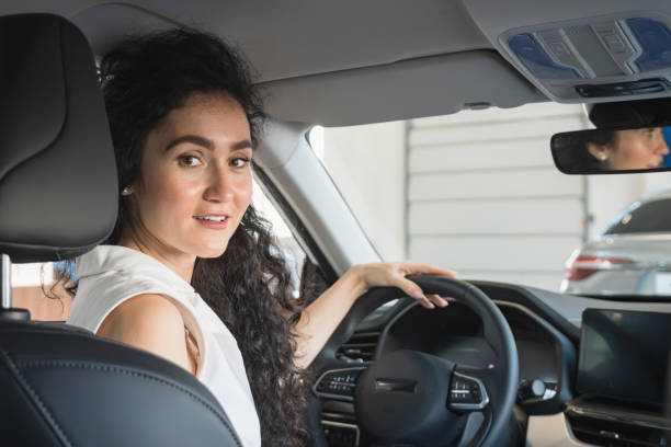 Businesswoman enjoys new car and sits with happy expression