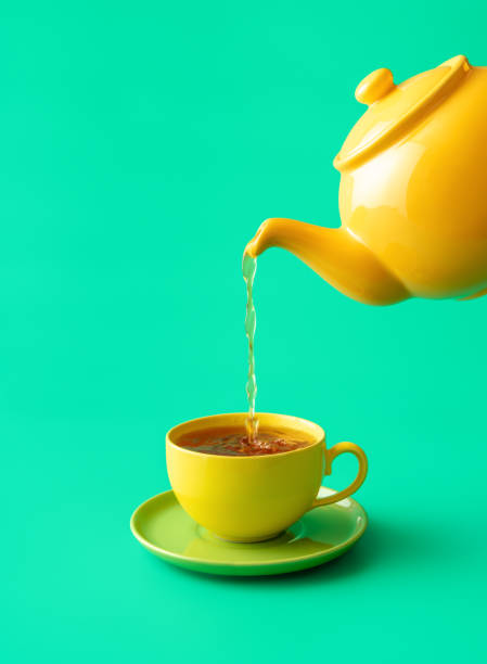 Pouring tea in a cup minimalist on a green background. stock photo