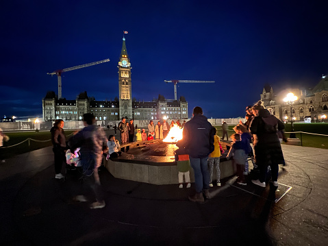 Ottawa, Ontario, Canada - October 15, 2022:  People gather around the Centennial Flame in from of the Parliament Building on Parliament Hill in Ottawa.