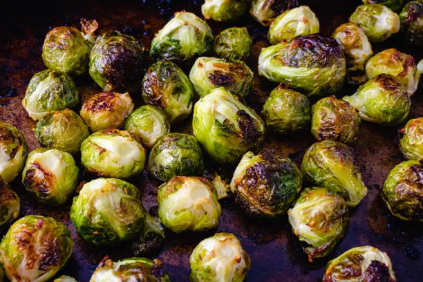 Brussels sprouts that have been baked in garlic butter on a rustic baking pan