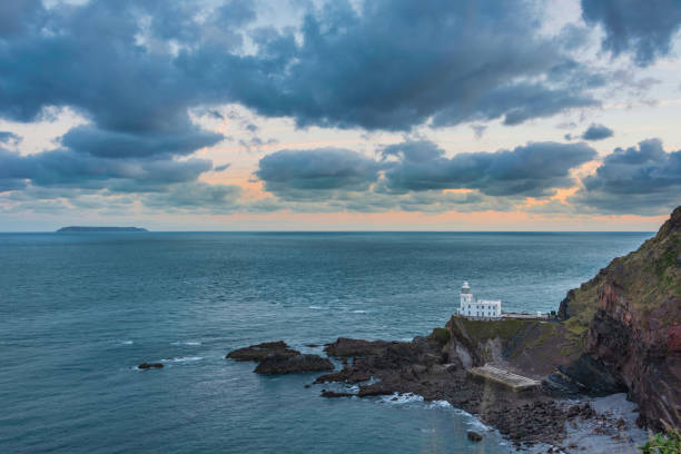 belle image du paysage du lever du soleil de la côte du devon en angleterre avec une lumière d’heure dorée époustouflante sur la terre et le ciel - hartland point lighthouse photos et images de collection