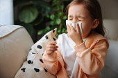 Little girl gets cold and blows her nose at home.