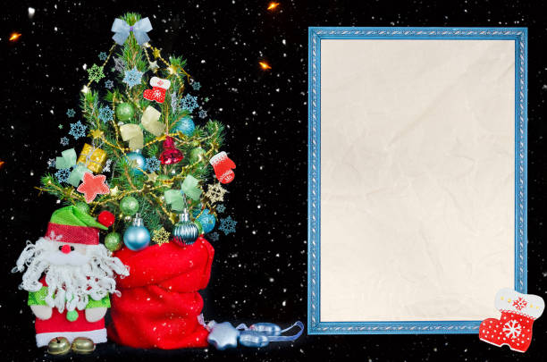 Christmas black background with falling snow, a decorated Christmas tree, a toy Santa and a text frame with blank paper