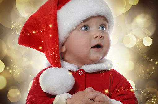 Cute baby in Christmas costume against blurred festive lights, closeup