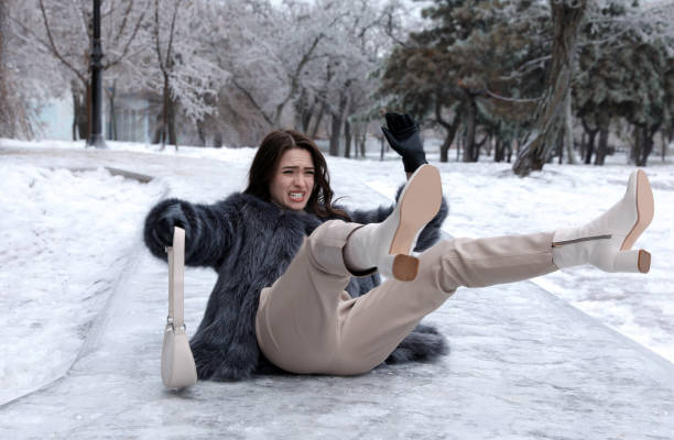 junge frau auf rutschiges, eisiges pflaster im park gefallen - ice winter white women stock-fotos und bilder