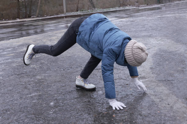 junge frau hat schwierigkeiten, sich auf vereisten straßen im freien zu bewegen - ice winter white women stock-fotos und bilder