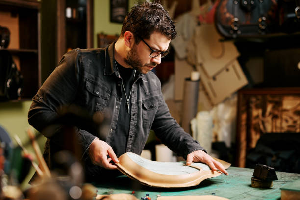 istock Portrait of leather craftsman makes a leather motorcycle seat at table in workshop studio 1441236441