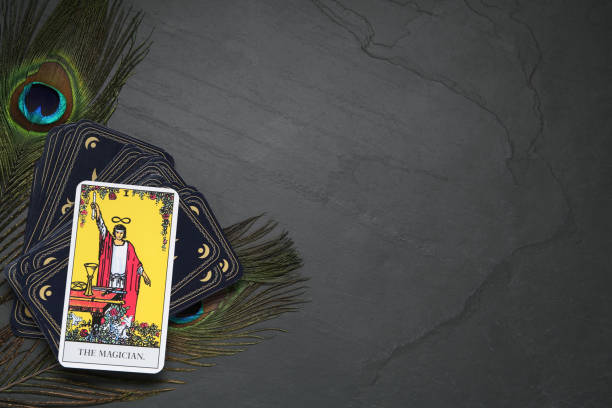 The Magician and other tarot cards with peacock feathers on black table, flat lay. Space for text