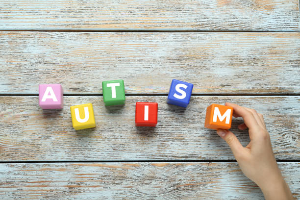 istock Woman making word Autism with colorful cubes on light wooden table, top view 1441237401