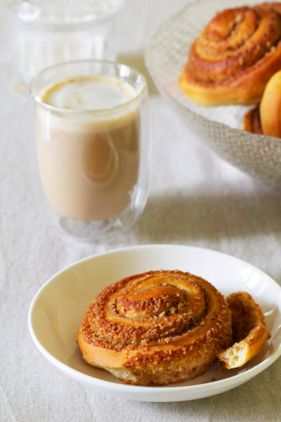 istock Cinnamon buns with nuts served with cappuccino on a linen tablecloth. Useful breakfast. 1441238329