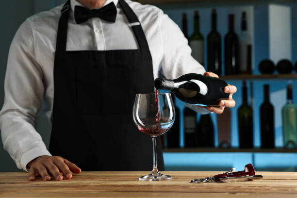 istock Bartender pouring wine into glass at counter in restaurant, closeup 1441240094