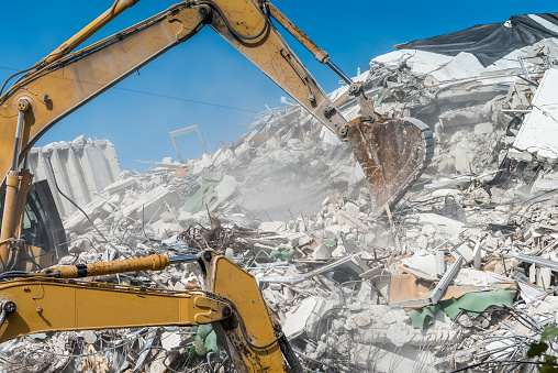 Engineer or Safety officer holding hard hat with the heavy equipment excavator demolition demolish machine in construction site.