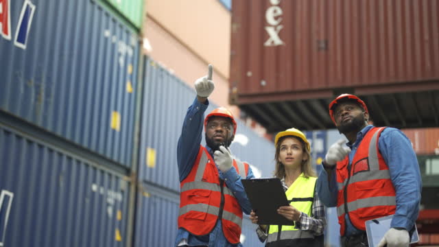 Multiracial Group Of Engineers Working Together In Shipping Yard