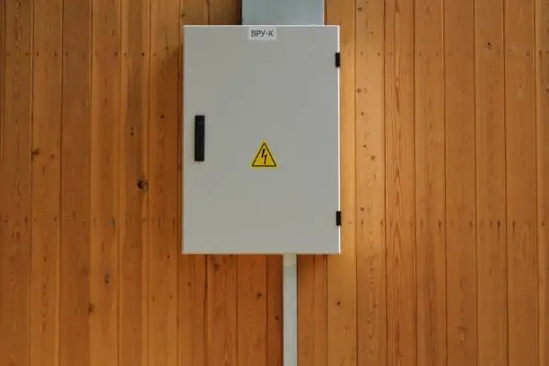 Photo of Knife switch and high voltage hazard sign on the wooden wall of house.