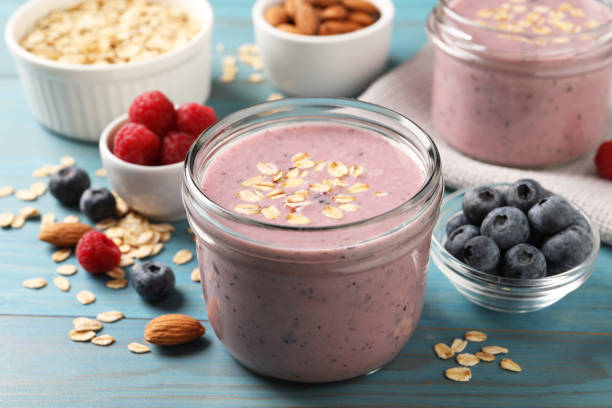 leckerer beeren-smoothie mit haferflocken auf hellblauem holztisch - jar oatmeal granola glass stock-fotos und bilder