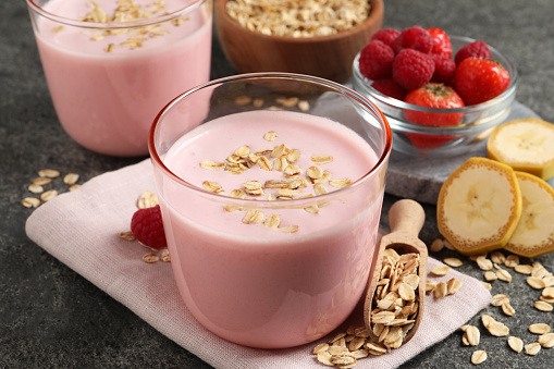 Glass of tasty berry smoothie with oatmeal on grey table