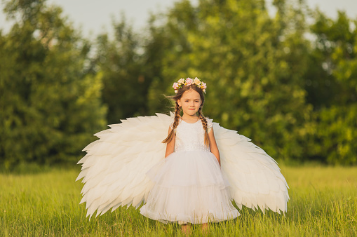 Portrait of happy angel wearing white clothing and wings over blue background     Note to inspector: the image is pre-Sept 1 2009