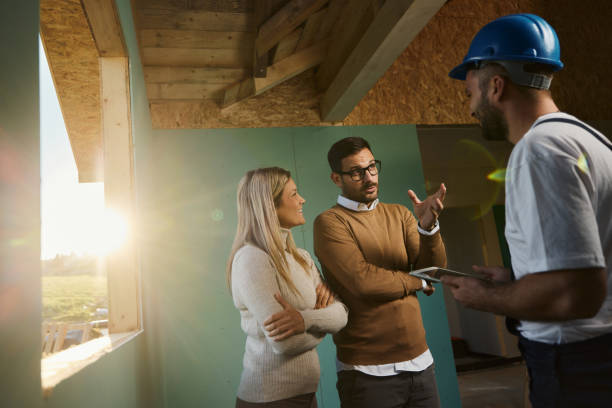 istock Young couple talking to manual worker at construction site. 1441249243