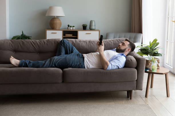 istock Man use modern smartphone lying on sofa in living room 1441251659
