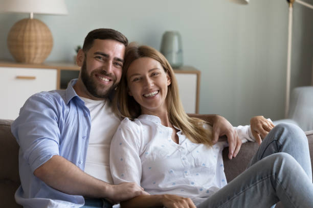istock Beautiful spouses posing for camera seated on sofa at home 1441251667