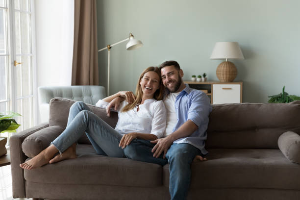 istock Millennial couple in love sit on sofa staring at camera 1441251669