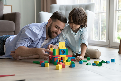 Father play with preschooler son use wooden multicoloured blocks