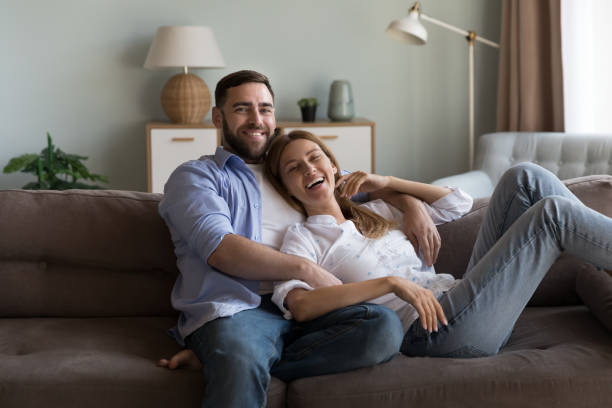 istock Couple relaxing on sofa laughing look at camera feel happy 1441252166