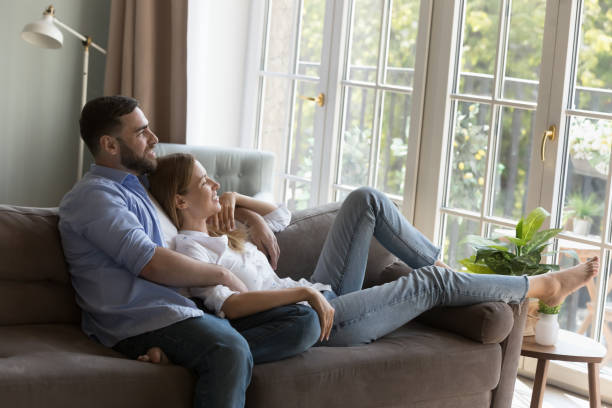 istock Couple in love relaxing on couch daydreaming looking out window 1441252169