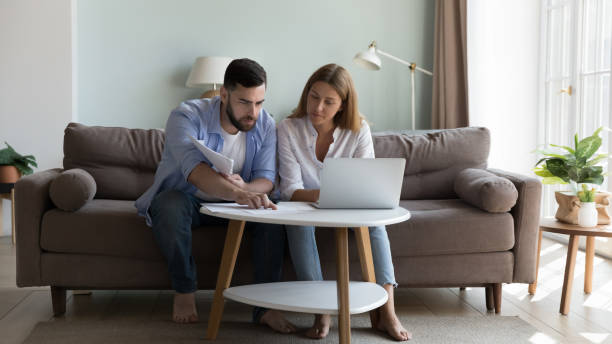 istock Serious millennial couple sit on sofa sorting out papers 1441252170